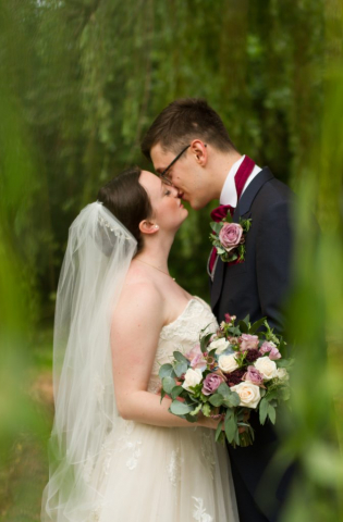 Bride and Groom kissing under a willow tree at Norfolk venue