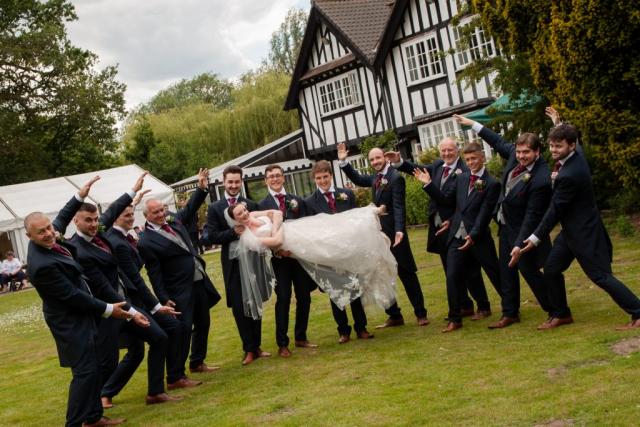 Bride being held up by groom and grooms men at Norfolk venue