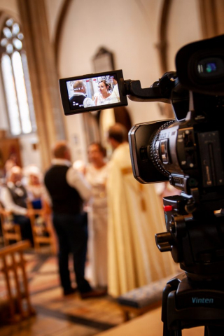 Bride and groom through videographers screen at St Marys Church Attleborough