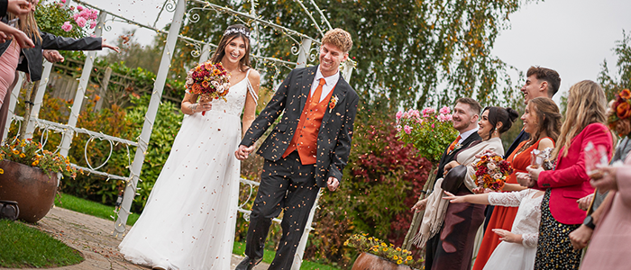 AlanBulldeathPhotographyBanner11 Bride and Groom walking through confetti smiling at Applewood hall Banham